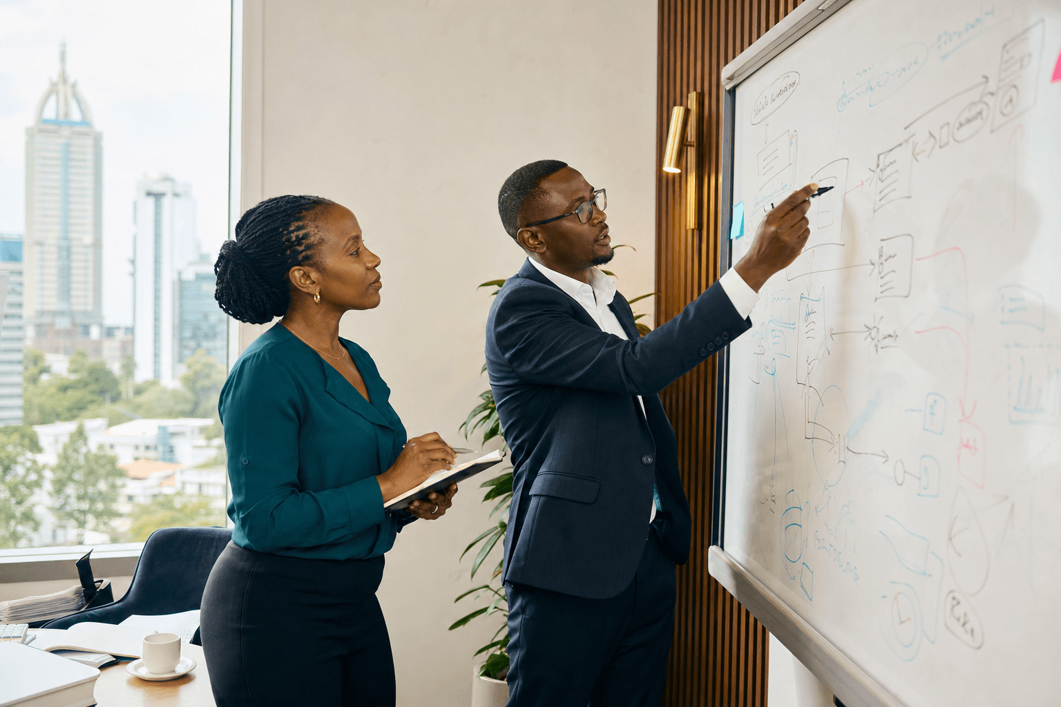 East African consultants reviewing a workflow on a whiteboard